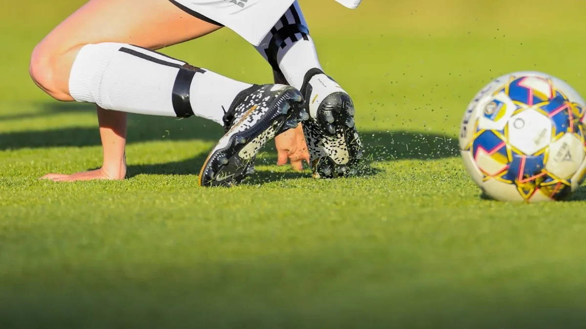 Fotbollsspelare slår till bollen på en grön gräsplan.